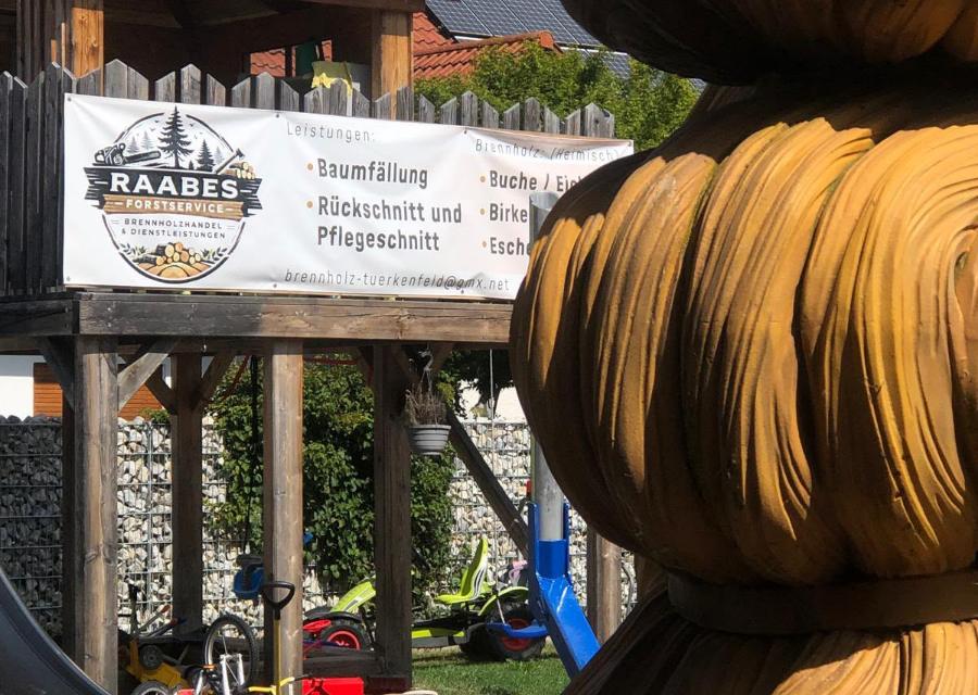 Banner von Raabes Forstservice neben dem Haar des Bavaria-Kopfes an der Werkstatt in Türkenfeld