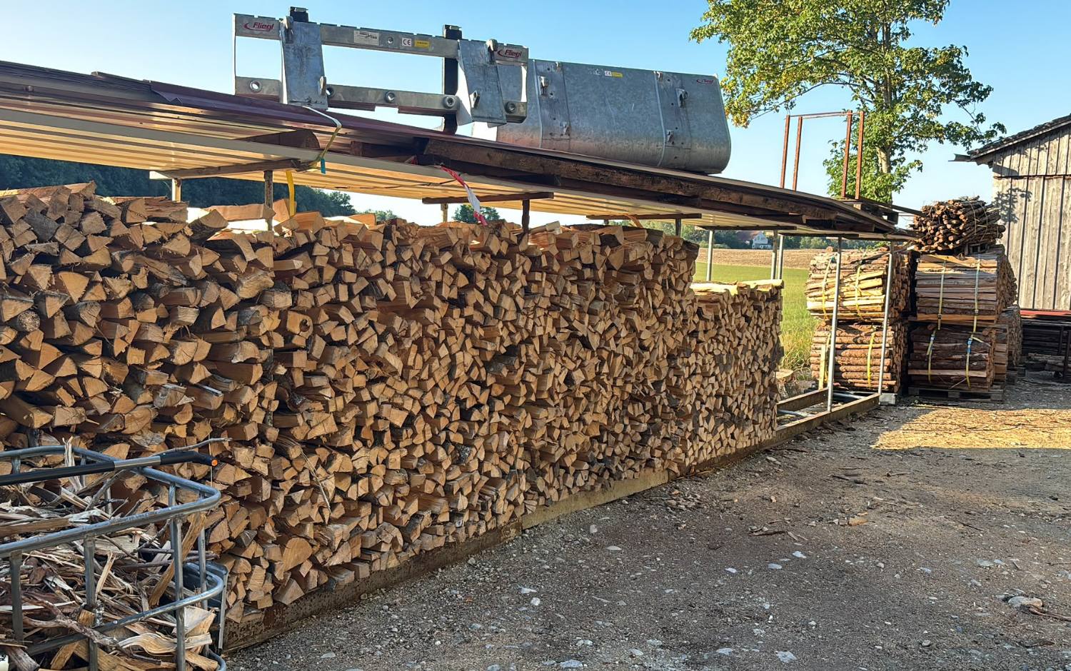 Langer, mannshoher Stapel gespaltener Scheite unter dem Vordach am Holzlagerplatz von Raabes Forstservice in Türkenfeld