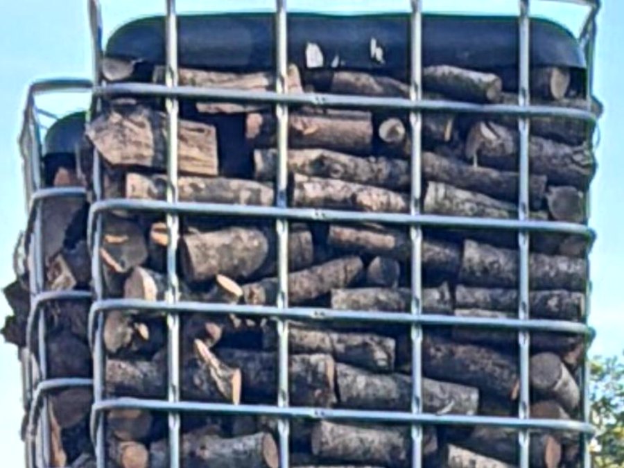 Gestapelte, mit Brennholz gefüllte IBC-Gitterkörbe am Betriebsgelände von Raabes Forstservice