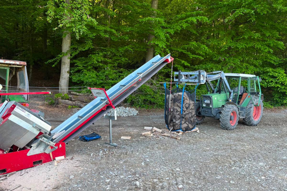 Collino Halbautomatik-Säge mit ausgefahrenem Förderband befüllt einen WoodBag am Waldrand
